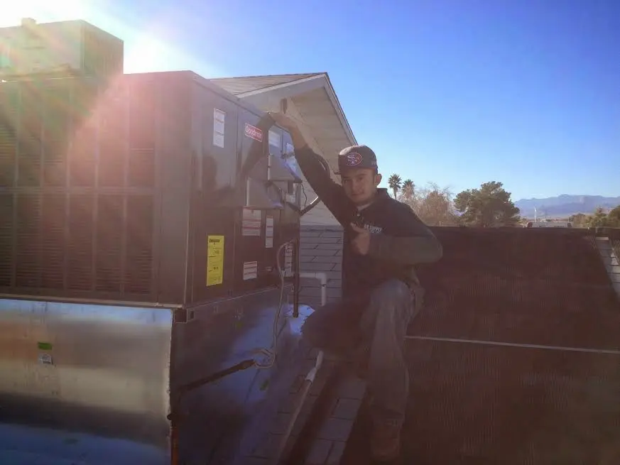 HVAC technician performing AC Tune-Up on a rooftop unit in Monroe